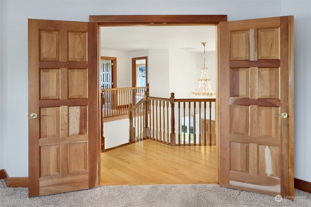 corridor with wood-type flooring and an inviting chandelier