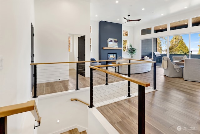 recreation room with a towering ceiling, ceiling fan, and hardwood / wood-style flooring