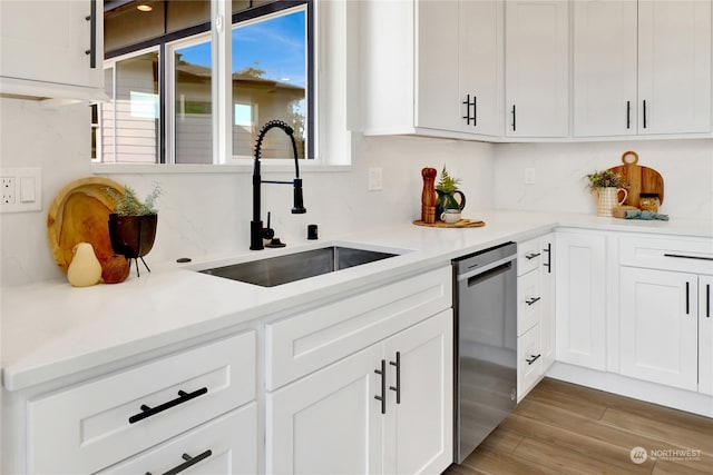 kitchen with sink, light hardwood / wood-style flooring, backsplash, white cabinetry, and dishwasher