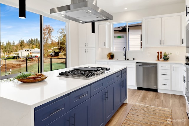 kitchen with light wood-type flooring, a kitchen island, stainless steel appliances, extractor fan, and blue cabinetry