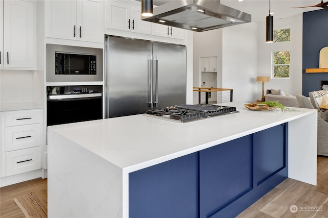 kitchen with white cabinets, built in appliances, light hardwood / wood-style floors, and range hood