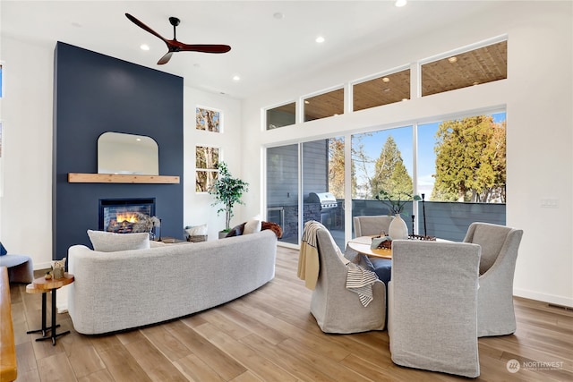 living room with wood-type flooring, ceiling fan, and a high ceiling