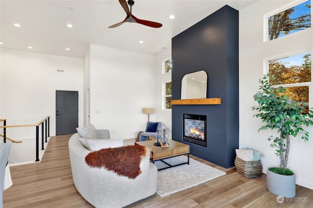 living room featuring light hardwood / wood-style flooring, a towering ceiling, and a healthy amount of sunlight