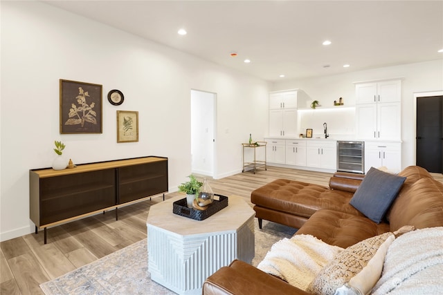 living room featuring light hardwood / wood-style flooring, wine cooler, and sink