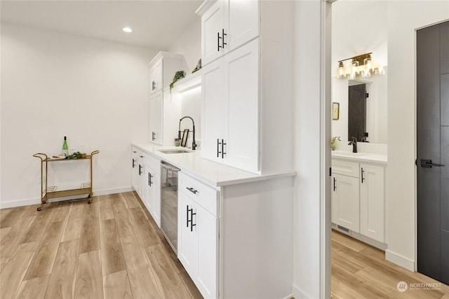 kitchen with white cabinets, dishwasher, light hardwood / wood-style floors, and sink