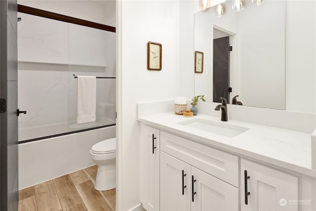 full bathroom with enclosed tub / shower combo, hardwood / wood-style floors, vanity, and toilet