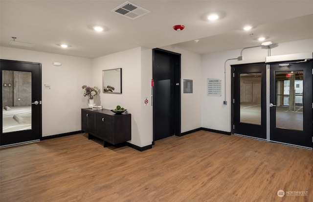 interior space featuring elevator, baseboards, visible vents, and light wood finished floors