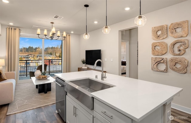 kitchen featuring dark wood-type flooring, decorative light fixtures, sink, and a center island with sink