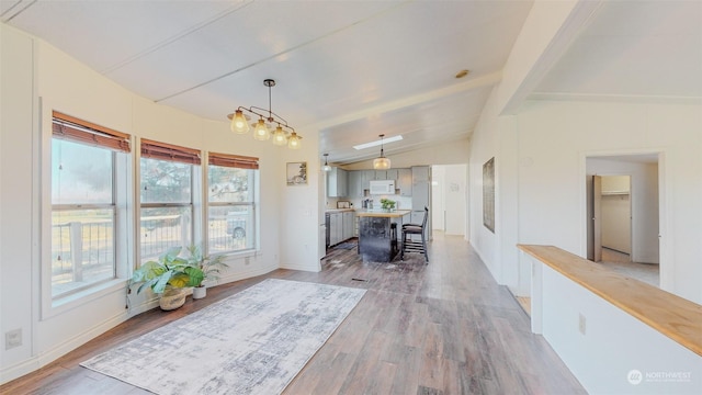 interior space featuring baseboards, vaulted ceiling with beams, and light wood-style floors