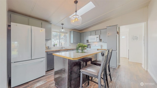 kitchen with light wood-style flooring, a sink, vaulted ceiling with skylight, gray cabinetry, and white appliances