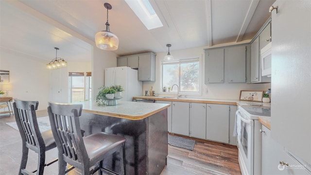 kitchen with a healthy amount of sunlight, gray cabinets, a sink, and white appliances