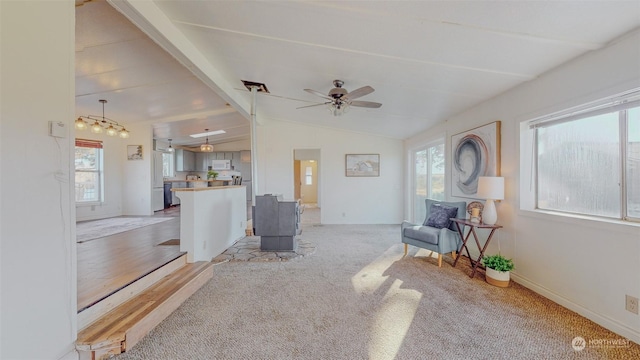living area with baseboards, ceiling fan, light colored carpet, and lofted ceiling with beams