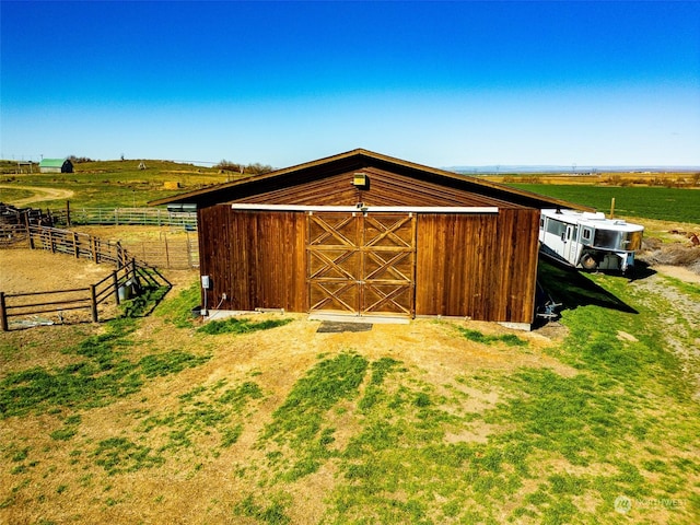 view of outdoor structure featuring an outdoor structure, a rural view, and fence