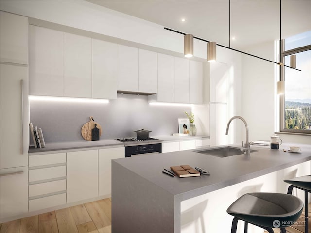 kitchen with wall oven, white cabinetry, sink, and a kitchen bar