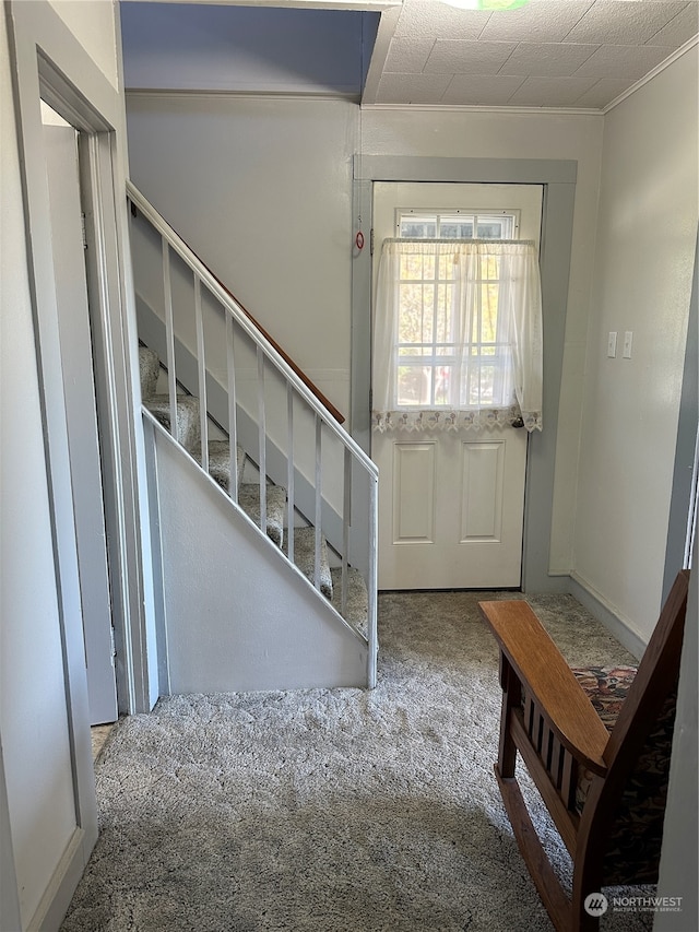 entrance foyer featuring a textured ceiling, crown molding, and carpet flooring