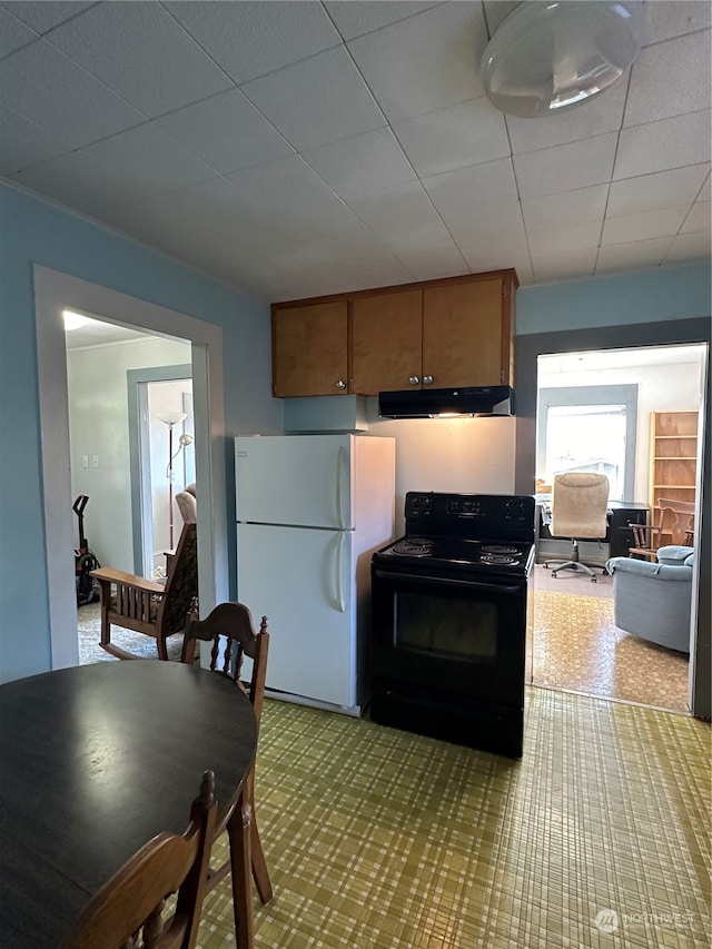 kitchen featuring a drop ceiling, electric range, and white fridge