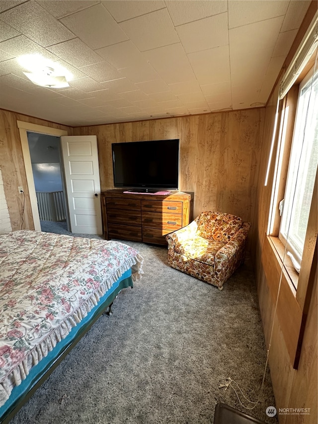 carpeted bedroom featuring wooden walls