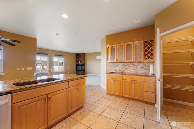 kitchen featuring light stone countertops, dishwasher, backsplash, and sink