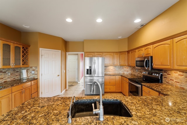 kitchen featuring dark stone counters, stainless steel appliances, backsplash, and sink