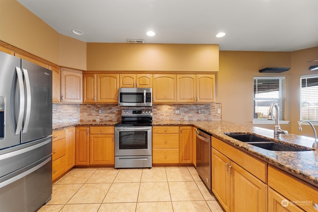 kitchen with decorative backsplash, light tile patterned floors, stainless steel appliances, stone counters, and sink