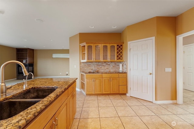 kitchen featuring decorative backsplash, light tile patterned floors, light stone countertops, and sink