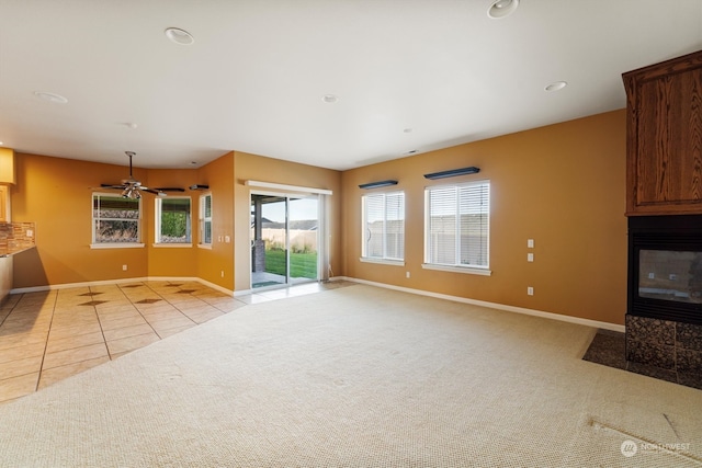 unfurnished living room featuring ceiling fan, light colored carpet, and a fireplace