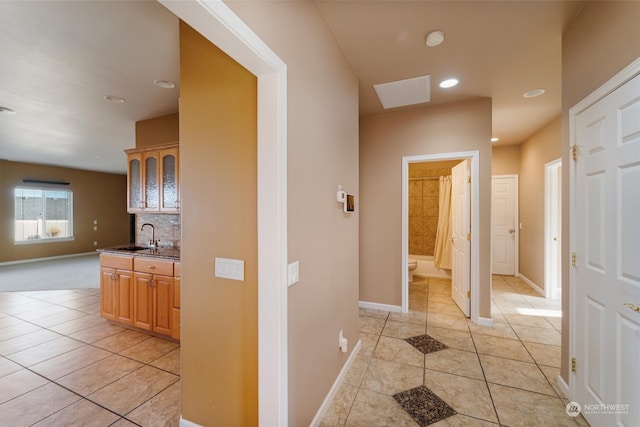 hallway with a skylight, light tile patterned floors, and sink