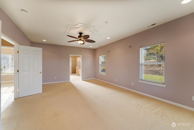 carpeted empty room with ceiling fan and plenty of natural light