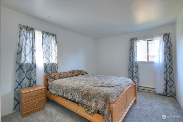 bedroom with a baseboard heating unit and light colored carpet