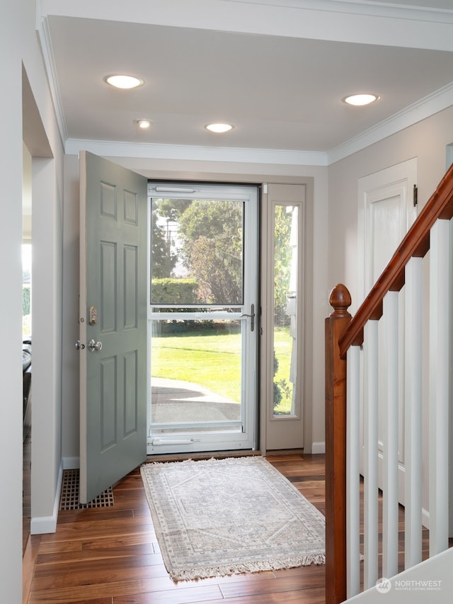 foyer with ornamental molding and dark hardwood / wood-style floors