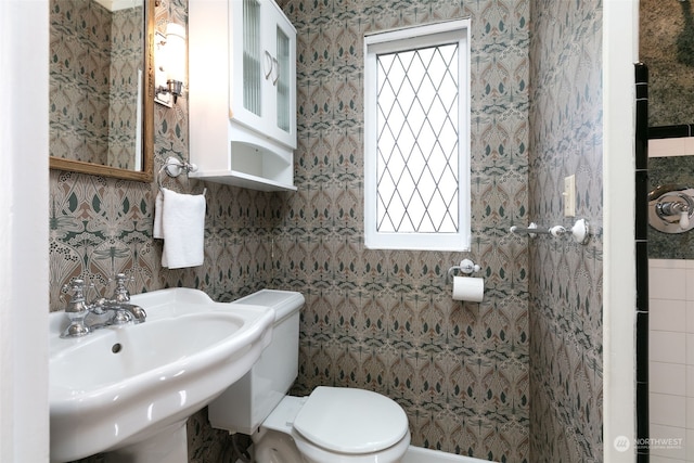 bathroom with tile walls, sink, and toilet