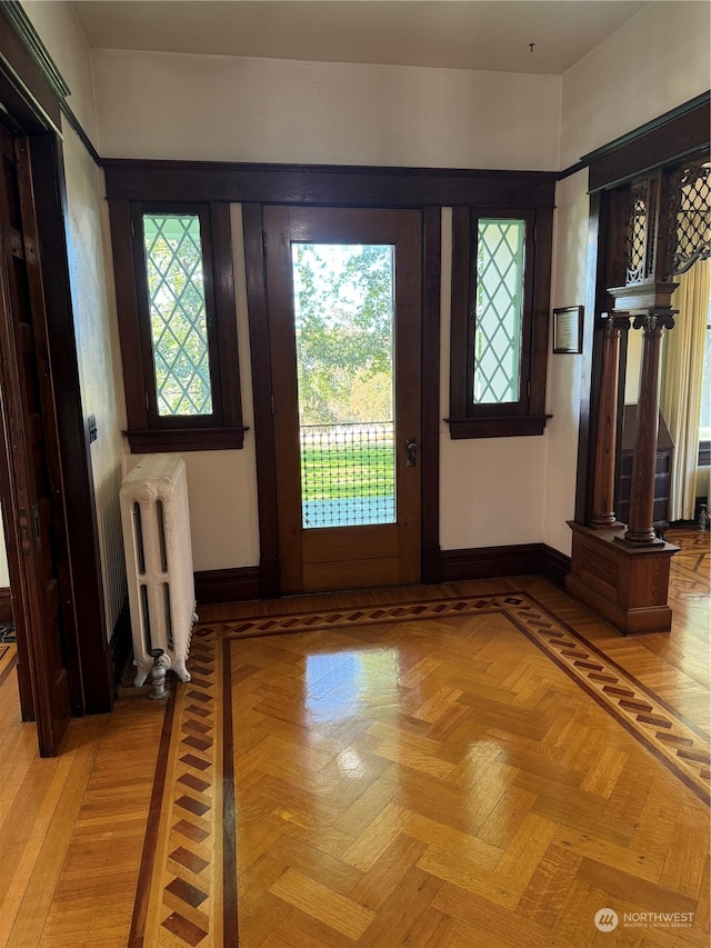 doorway with ornate columns, light parquet floors, and radiator