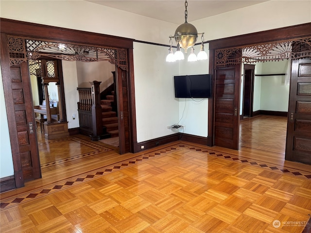 unfurnished dining area featuring an inviting chandelier and parquet flooring