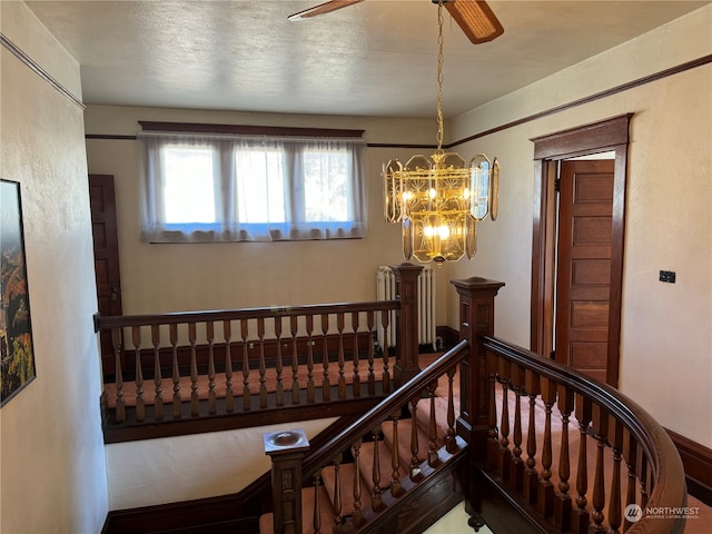 stairway with a textured ceiling and a notable chandelier