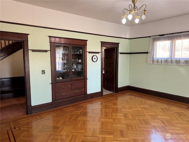 empty room featuring an inviting chandelier and light parquet flooring