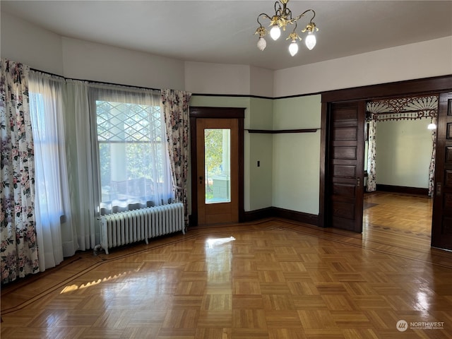 unfurnished room featuring a notable chandelier, radiator heating unit, and light parquet flooring