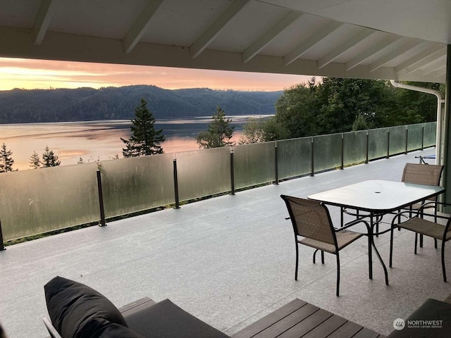 patio terrace at dusk featuring a water and mountain view