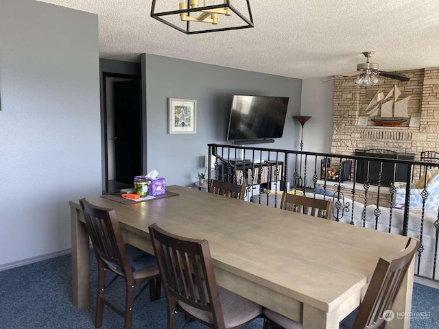 dining space with ceiling fan, a textured ceiling, carpet flooring, and a fireplace