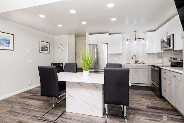 kitchen featuring dark hardwood / wood-style flooring, stainless steel appliances, hanging light fixtures, white cabinets, and a center island