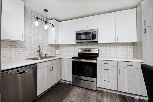 kitchen with stainless steel appliances, pendant lighting, white cabinets, and dark hardwood / wood-style flooring