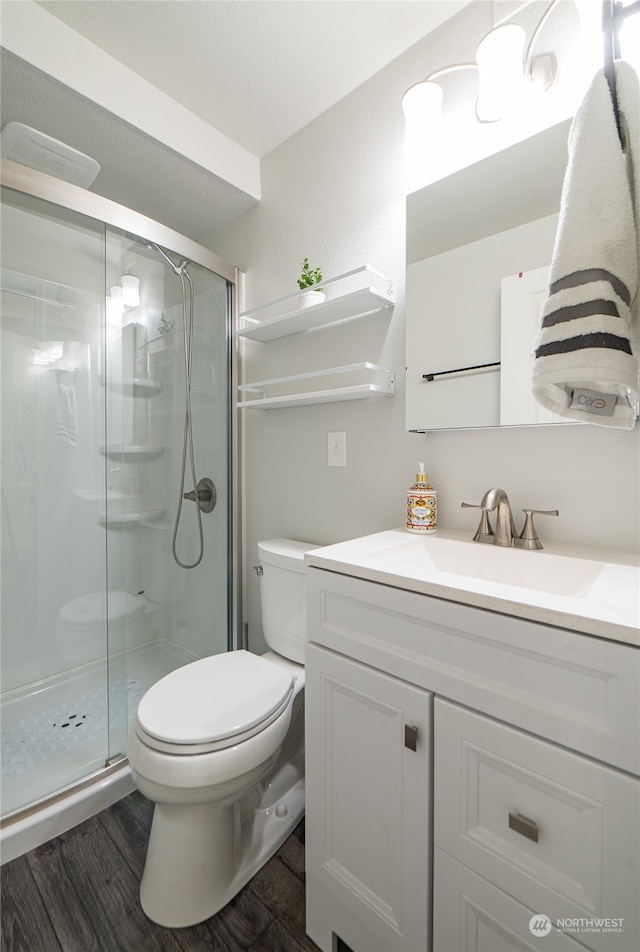 bathroom with an enclosed shower, hardwood / wood-style flooring, vanity, and toilet