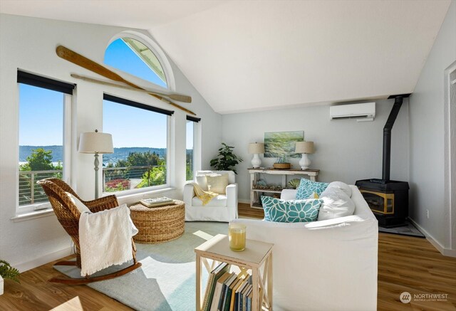 living room featuring a wood stove, hardwood / wood-style floors, lofted ceiling, a mountain view, and a wall mounted AC