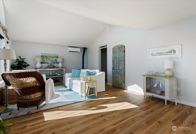 living room featuring a wall mounted AC, lofted ceiling, and hardwood / wood-style floors