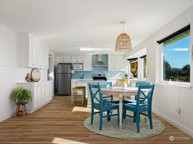 dining area with light hardwood / wood-style floors and wooden walls