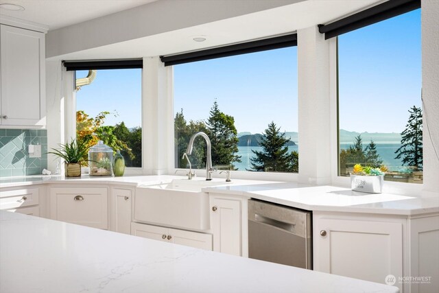 kitchen featuring dishwasher, white cabinets, and a water view