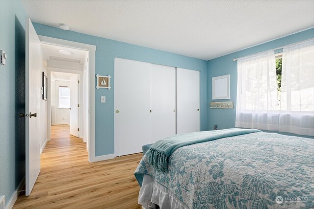 bedroom with a closet, a textured ceiling, and light hardwood / wood-style floors