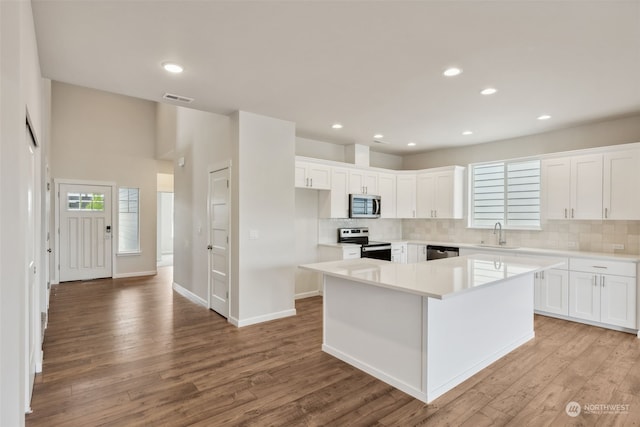 kitchen featuring visible vents, a sink, a center island, light wood-style floors, and appliances with stainless steel finishes