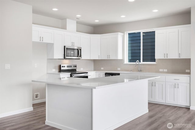 14727 88th Way SE Unit 18, Yelm, WA 98597 - kitchen with baseboards, a sink, backsplash, light wood-style floors, and appliances with stainless steel finishes