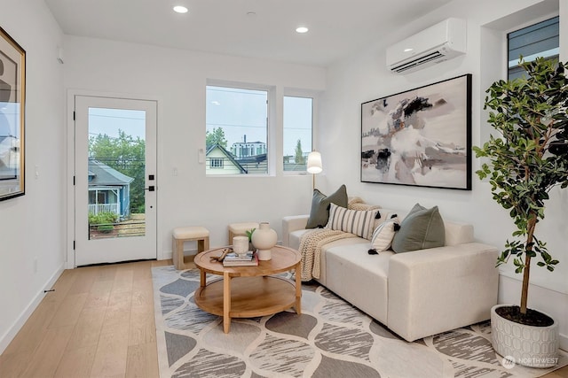 sitting room featuring a wall unit AC, a wealth of natural light, and light hardwood / wood-style floors