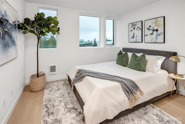 bedroom with hardwood / wood-style floors and multiple windows